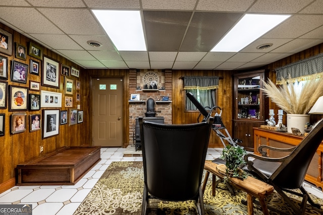 office area featuring brick wall, a drop ceiling, light tile patterned flooring, and wooden walls