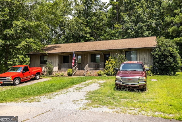 ranch-style house featuring covered porch and a front lawn