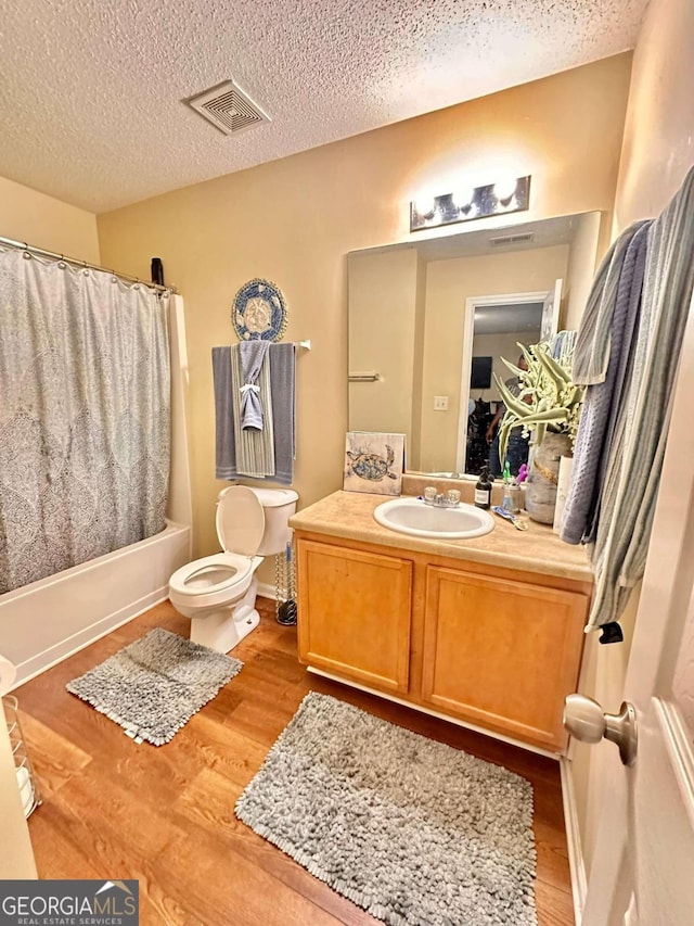 full bathroom featuring shower / bath combo with shower curtain, toilet, vanity, and a textured ceiling