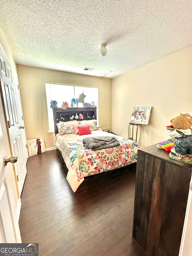 bedroom with a textured ceiling and wood-type flooring