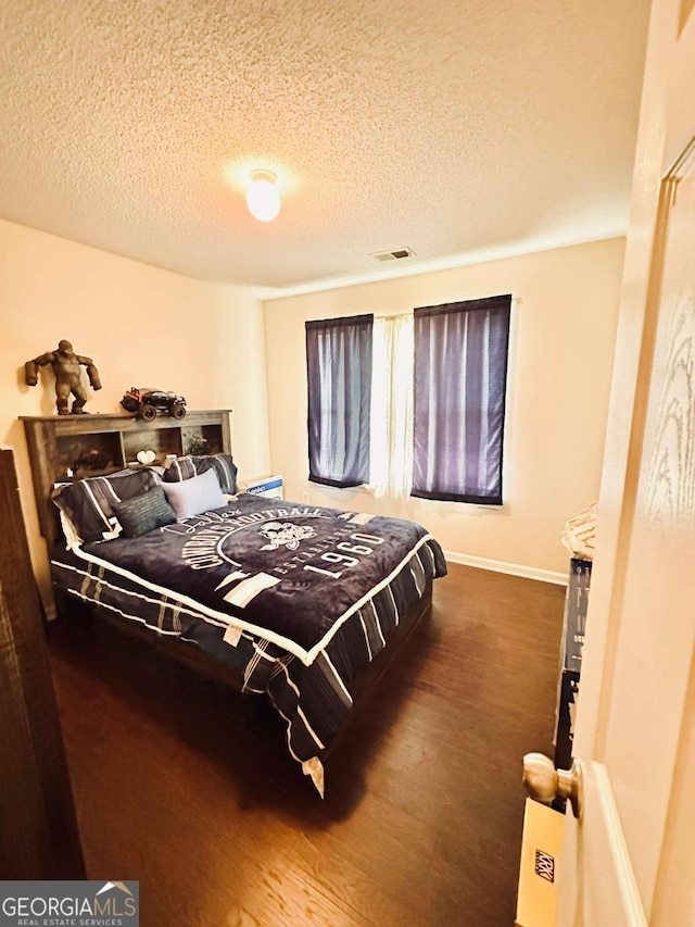 bedroom with a textured ceiling and wood-type flooring