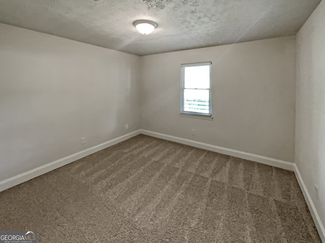 empty room with carpet floors and a textured ceiling