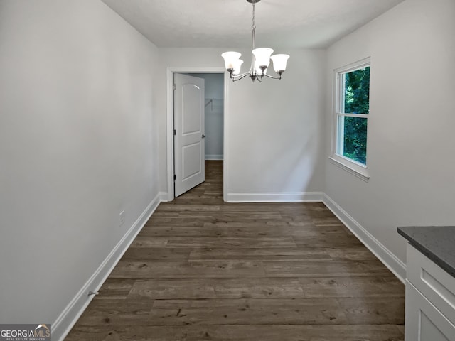 unfurnished dining area with dark hardwood / wood-style floors and a chandelier