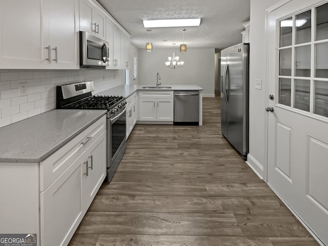 kitchen featuring appliances with stainless steel finishes, kitchen peninsula, sink, and dark wood-type flooring