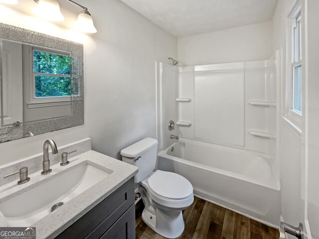 full bathroom with hardwood / wood-style flooring, shower / bath combination, toilet, and vanity