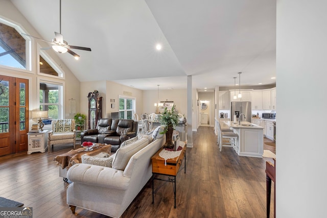 living room featuring ceiling fan with notable chandelier, dark hardwood / wood-style flooring, sink, and high vaulted ceiling