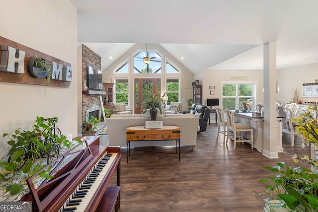 living room featuring high vaulted ceiling, a fireplace, ceiling fan, and dark hardwood / wood-style flooring