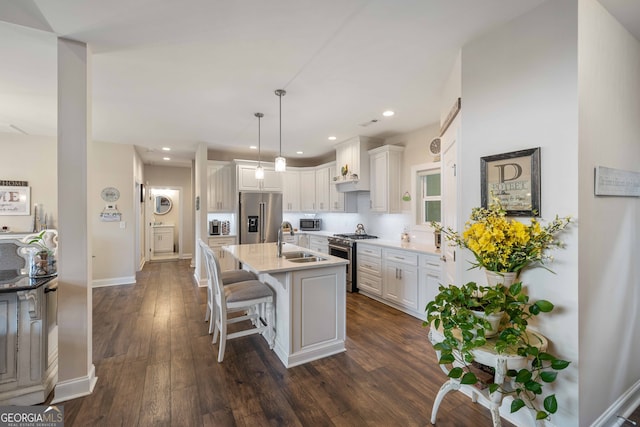 kitchen featuring white cabinetry, stainless steel appliances, dark hardwood / wood-style flooring, sink, and a kitchen island with sink