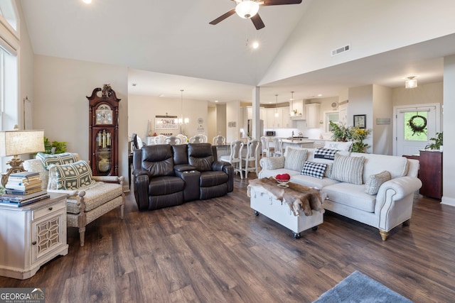 living room featuring dark wood-type flooring, ceiling fan with notable chandelier, and high vaulted ceiling