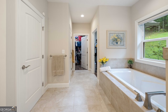 bathroom with a relaxing tiled tub and tile patterned floors