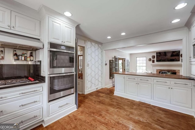 kitchen with white cabinetry, double oven, and light hardwood / wood-style floors