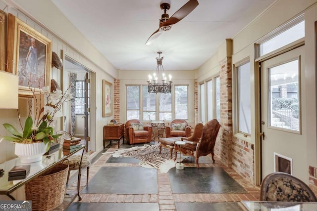 sunroom featuring ceiling fan with notable chandelier and a wealth of natural light