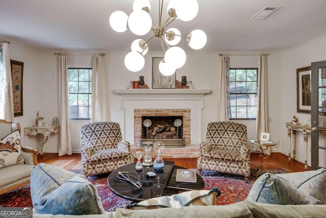 living room featuring wood-type flooring, plenty of natural light, ornamental molding, and a fireplace