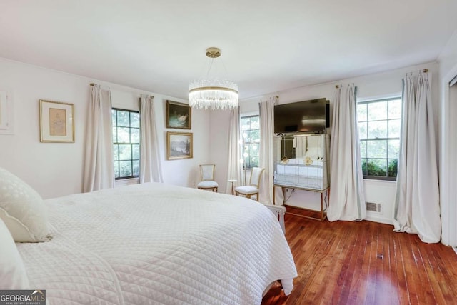 bedroom with an inviting chandelier, dark hardwood / wood-style flooring, and multiple windows