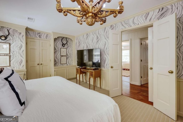 bedroom featuring an inviting chandelier, crown molding, and light hardwood / wood-style floors