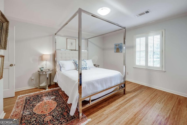 bedroom featuring crown molding and light hardwood / wood-style flooring