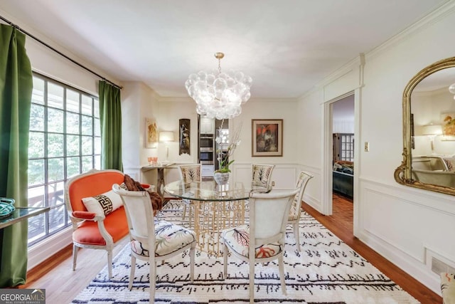 dining room with crown molding, light wood-type flooring, and an inviting chandelier