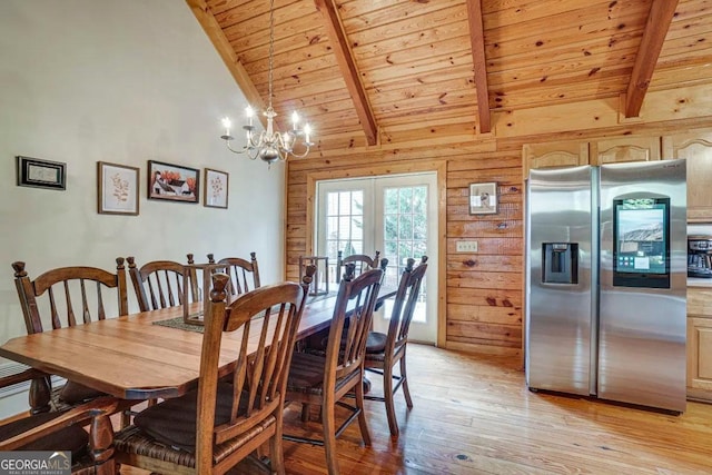 dining area featuring wood walls, a notable chandelier, light hardwood / wood-style floors, and lofted ceiling with beams