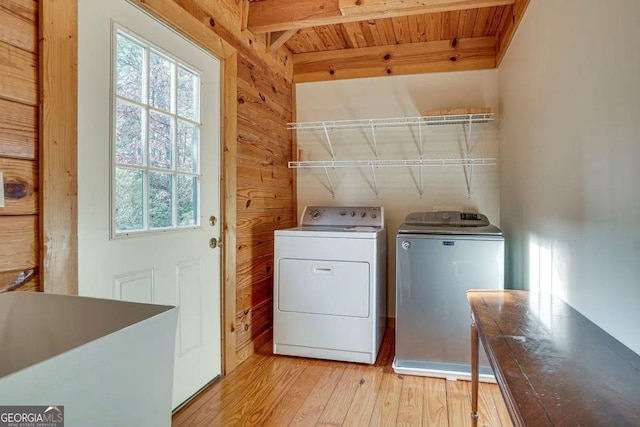 washroom with light wood-type flooring, wooden ceiling, separate washer and dryer, and wood walls