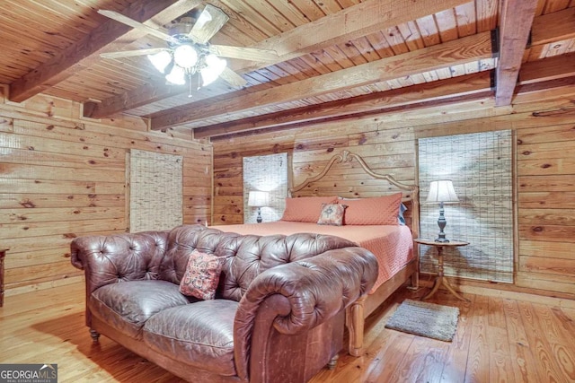 bedroom with beam ceiling, light hardwood / wood-style flooring, and wooden walls