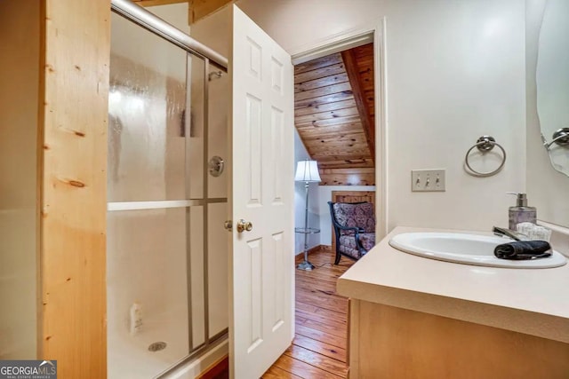 bathroom featuring wood walls, wood-type flooring, a shower with shower door, vanity, and lofted ceiling