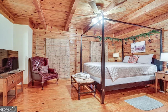 bedroom with beam ceiling, light hardwood / wood-style flooring, wooden ceiling, wooden walls, and ceiling fan