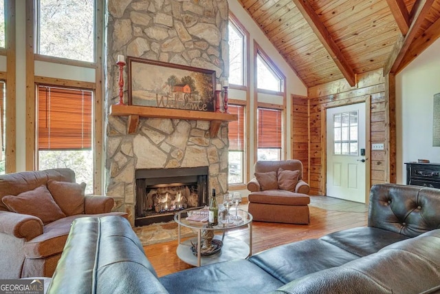 living room with a stone fireplace, high vaulted ceiling, hardwood / wood-style floors, wooden ceiling, and beamed ceiling