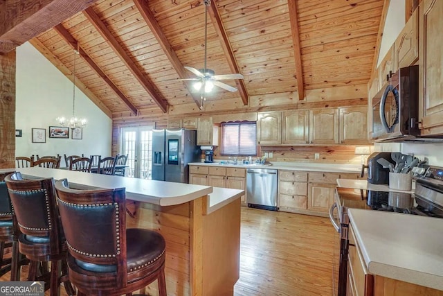 kitchen featuring light wood-type flooring, a kitchen breakfast bar, wood walls, beamed ceiling, and stainless steel appliances