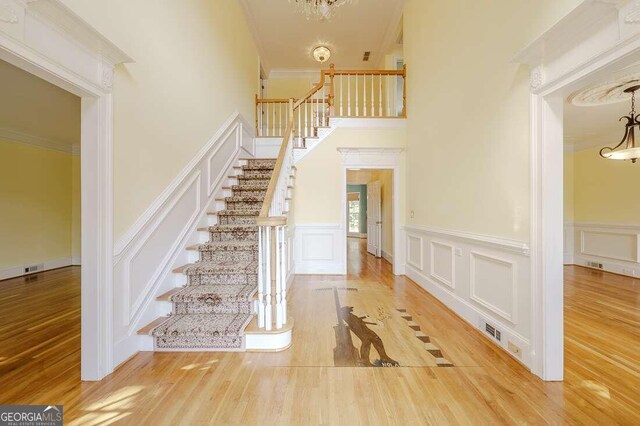 foyer with an inviting chandelier, hardwood / wood-style flooring, and crown molding