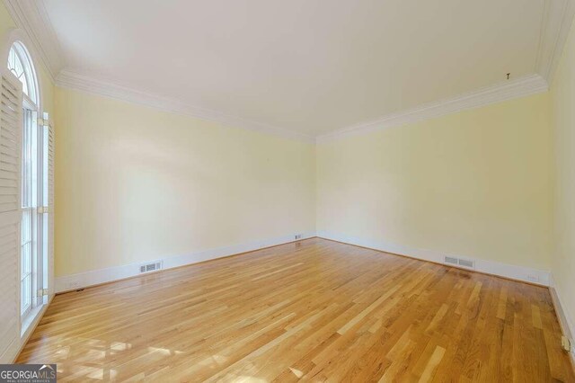 empty room with ornamental molding and light wood-type flooring