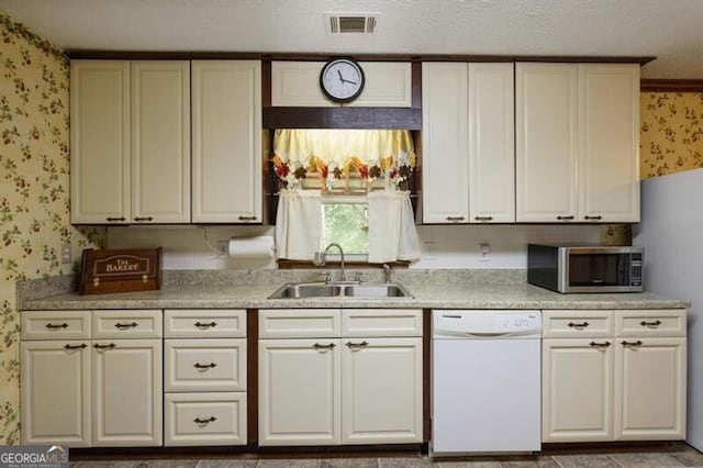 kitchen with sink, dishwasher, and a textured ceiling