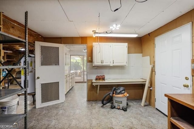 kitchen featuring white cabinets, light tile patterned flooring, and water heater