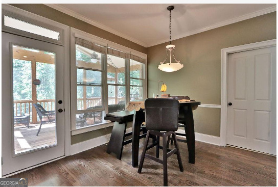 dining space featuring a wealth of natural light, crown molding, and dark wood-type flooring