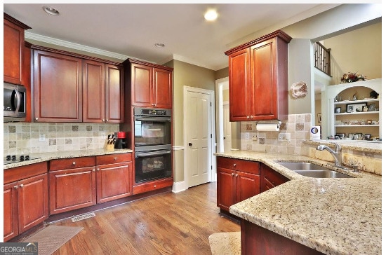 kitchen with gas stovetop, backsplash, double oven, hardwood / wood-style flooring, and sink