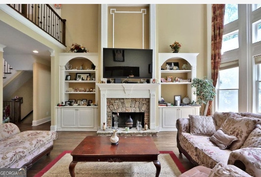 living room featuring a fireplace, hardwood / wood-style flooring, and a towering ceiling