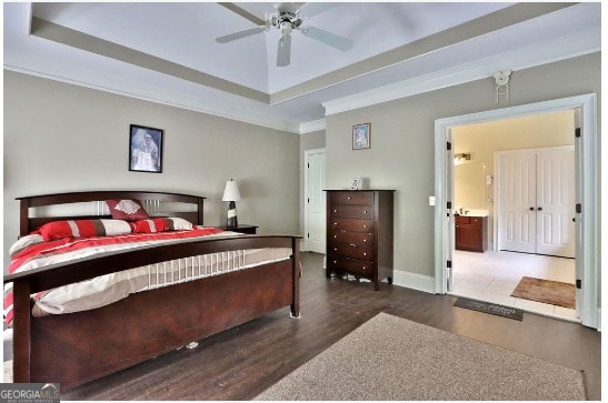 bedroom with connected bathroom, a raised ceiling, ceiling fan, wood-type flooring, and ornamental molding