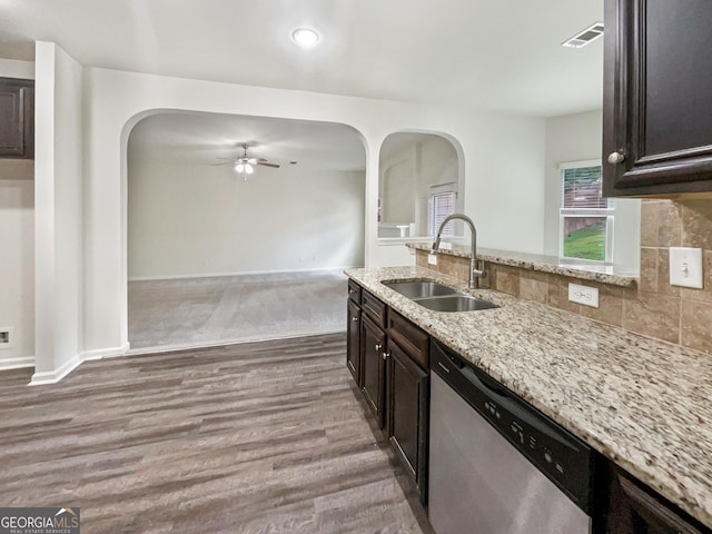 kitchen featuring sink, stainless steel dishwasher, light stone countertops, hardwood / wood-style floors, and backsplash