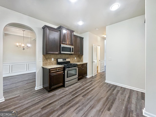 kitchen featuring tasteful backsplash, dark brown cabinets, appliances with stainless steel finishes, dark hardwood / wood-style floors, and a notable chandelier