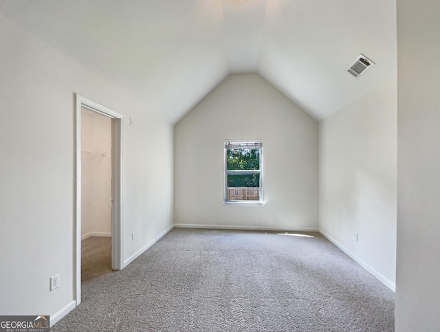 additional living space featuring vaulted ceiling and light carpet