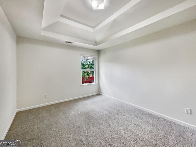 carpeted spare room with a tray ceiling