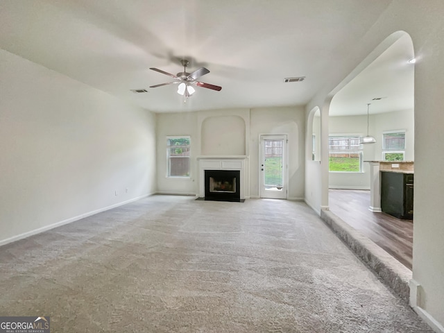 unfurnished living room featuring a wealth of natural light, light colored carpet, and ceiling fan