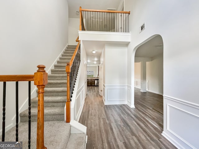 staircase with wood-type flooring and a high ceiling