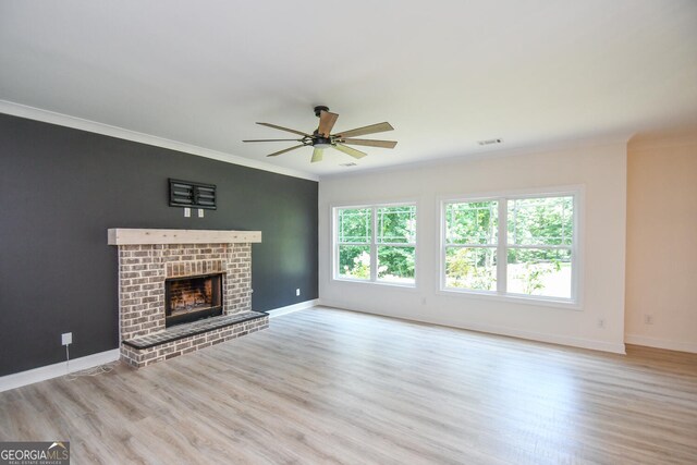 unfurnished living room with ceiling fan, light wood-type flooring, a brick fireplace, and ornamental molding