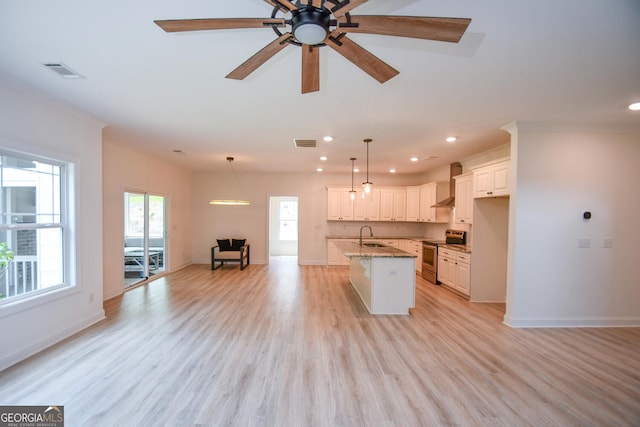 kitchen featuring white cabinets, a kitchen island with sink, electric range, light stone countertops, and wall chimney range hood