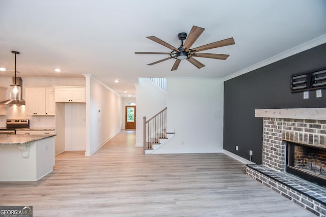 unfurnished living room featuring a brick fireplace, crown molding, and light hardwood / wood-style floors
