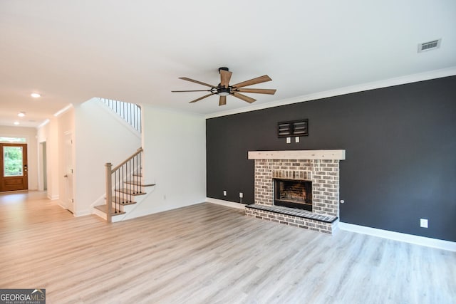 unfurnished living room with a brick fireplace, crown molding, light hardwood / wood-style flooring, and ceiling fan