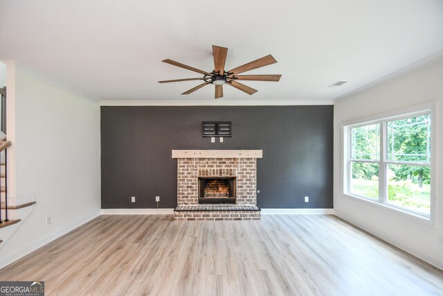 unfurnished living room with ceiling fan, ornamental molding, light hardwood / wood-style floors, and a brick fireplace