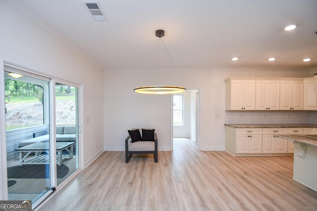 sitting room with ornamental molding and light wood-type flooring