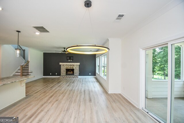 unfurnished living room featuring a fireplace, light hardwood / wood-style flooring, and ceiling fan