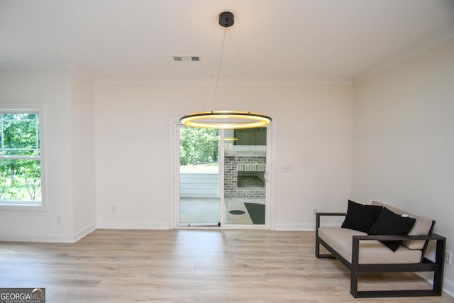 sitting room with crown molding and light wood-type flooring